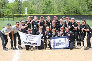 Softball team poses with conference trophy on field