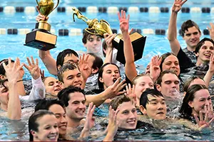 Swimmers in pool celebrate with trophy