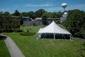 Large white tent outdoors in science quad surrounded by trees