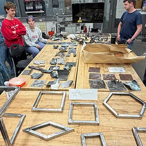 Welding class students with metalwork on table