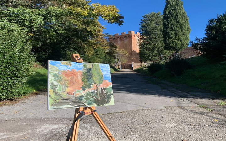 Easel in front of road and trees with painting of the view ahead