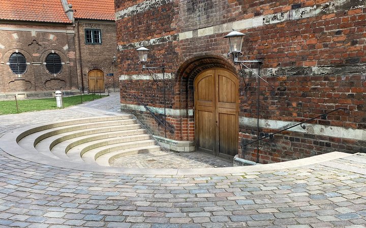 Circular arena leading down to wooden door on brick wall