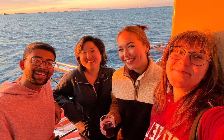 Students on deck of boat at sea with faces lit by sunset