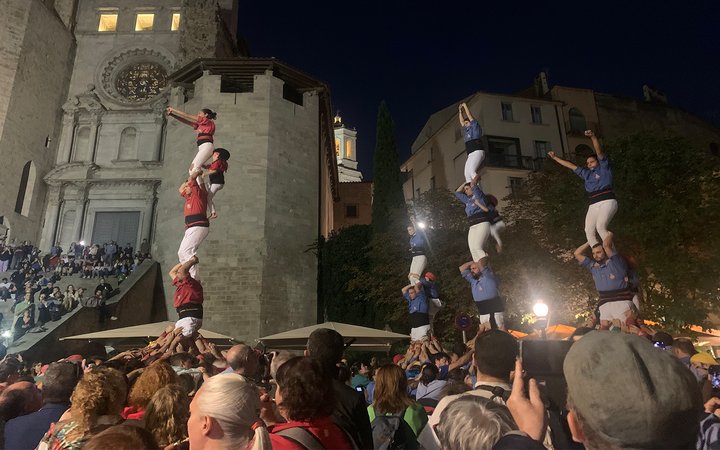 Audience watching outdoor show of people standing on top of each other (4 towers of up to 4 people)