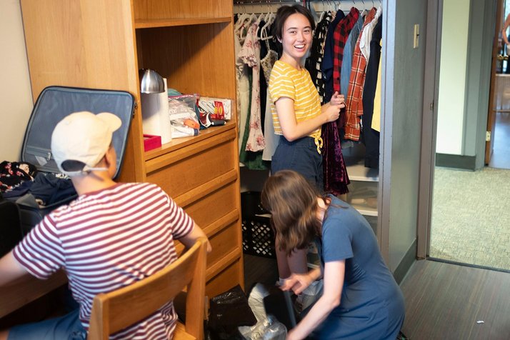 Person hangs clothes in dorm room closet
