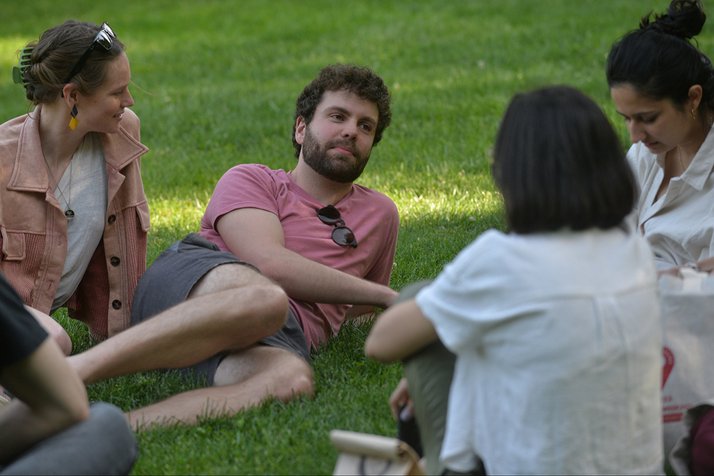 Alumni sit on grass and talk