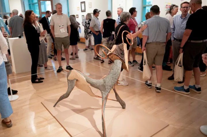 Group of alumni examine work in List Gallery