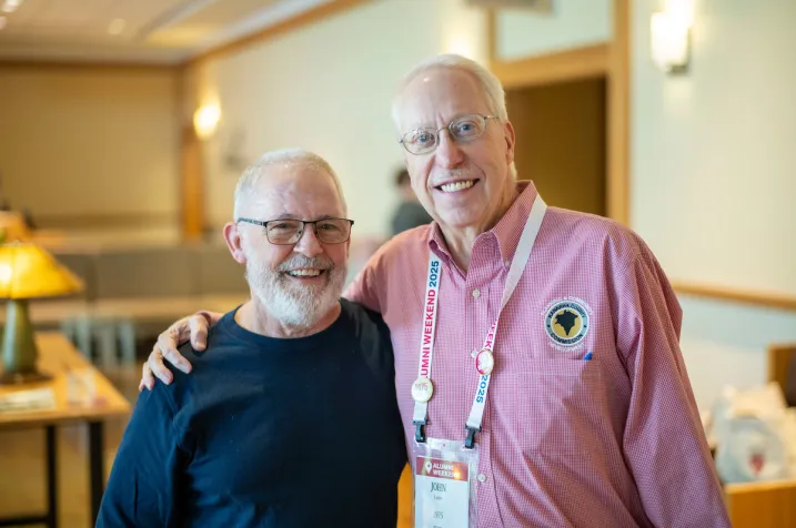 Two alumni smile and pose together