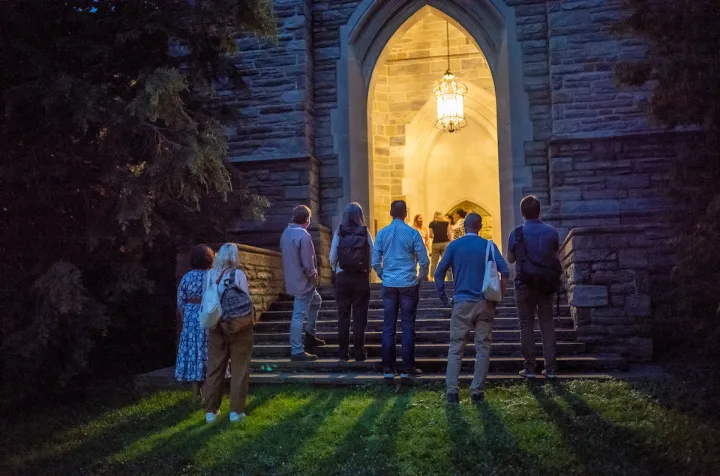 Alumni stand by clothier belltower alcove at night