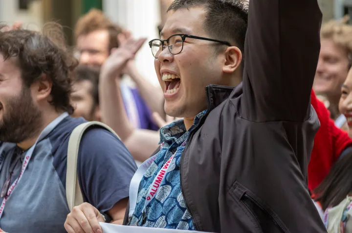 Smiling, waving alum at parade of classes