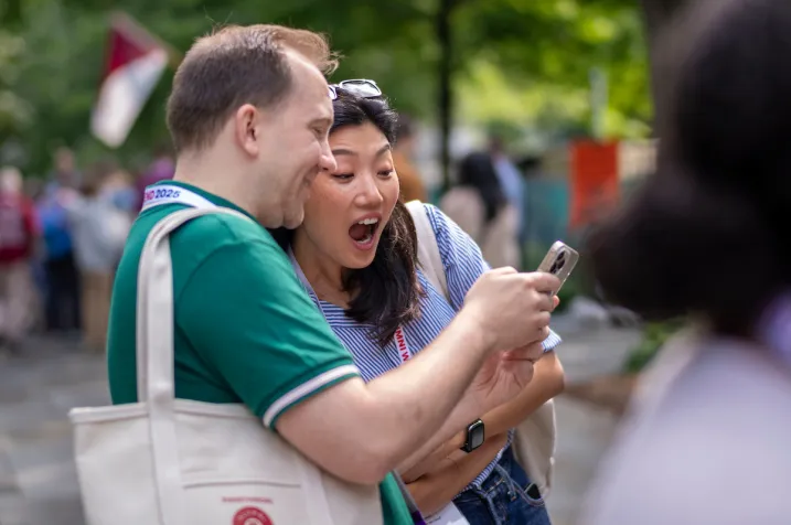 Two alums look at phone screen