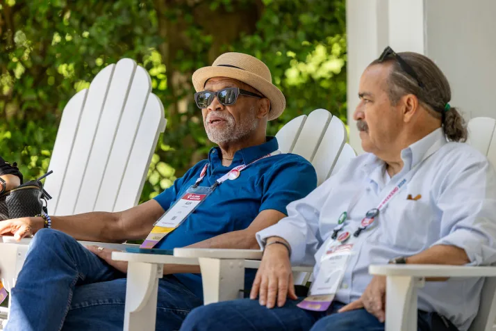 Two alums sit on white Adirondack chairs