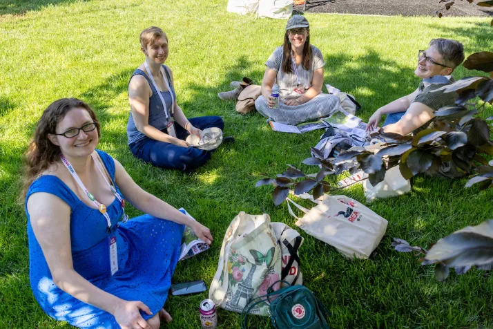 Alums sit outside on grass in circle