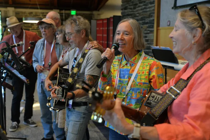Group of alumni play instruments and sing into microphones