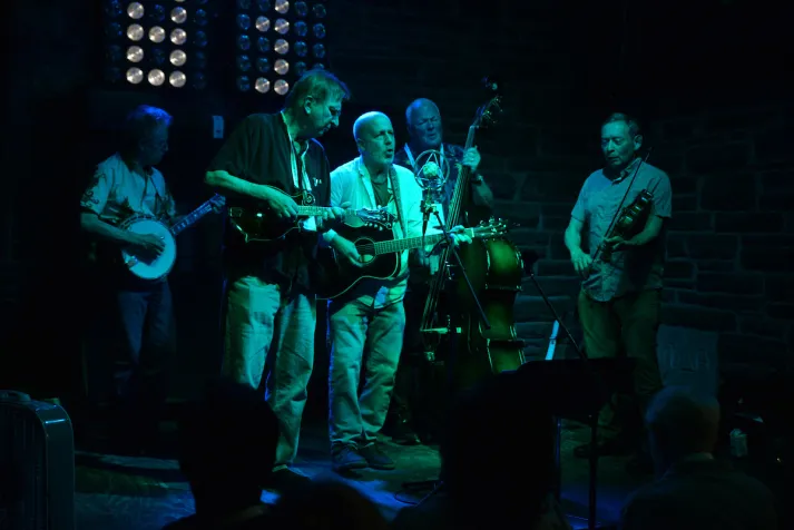 Alumni play guitars and sing on stage at evening event