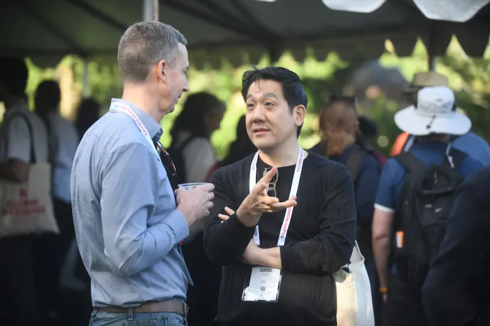 Two alums have conversation under outdoor tent