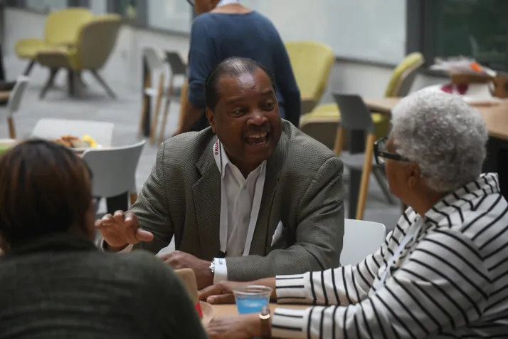 Two alums converse at table