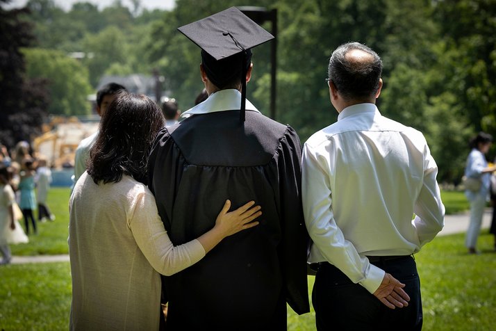Graduating student and parents pose with backs turned to camera