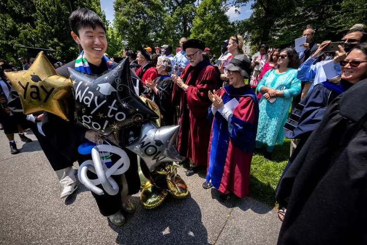 Student wearing cap and gown receives balloons