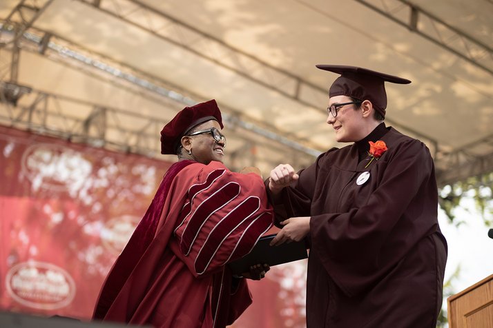 President Smith elbow bumps student while handing out diploma