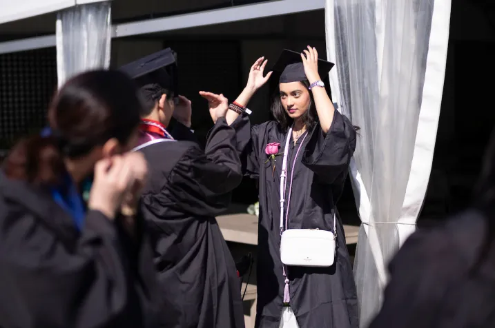 Students make last-minute adjustments to commencement regalia