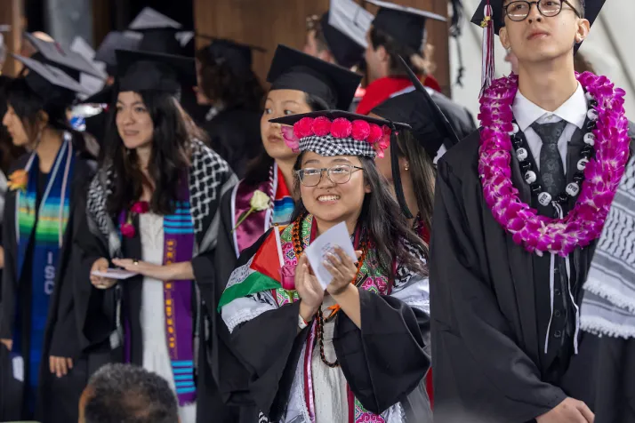 Students at commencement clap before getting on stage