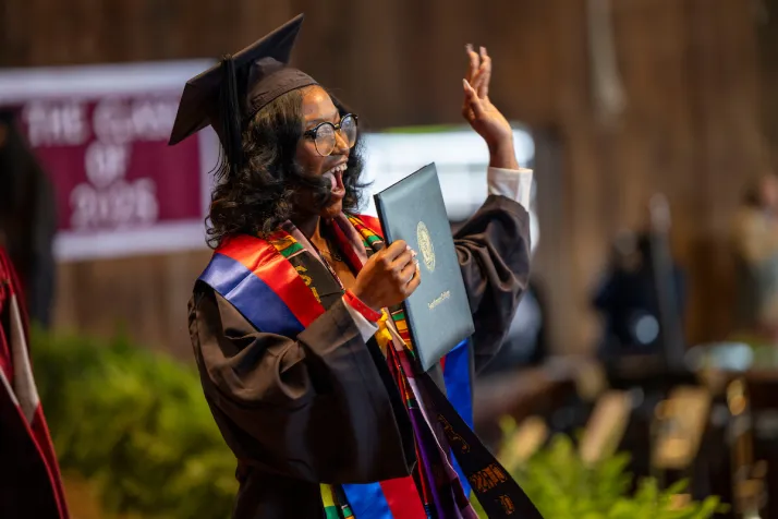 Student receives diploma and waves to crowd