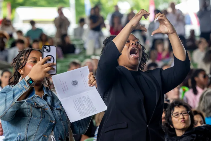 Family member in crowd makes heart symbol with hands