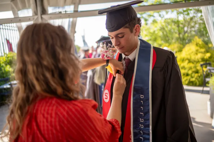 Student has rose pinned on commencement stole
