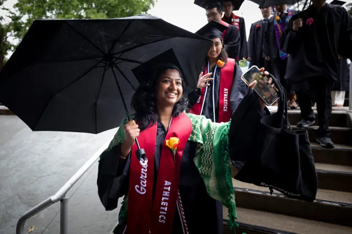 Student holds umbrella during graduation procession