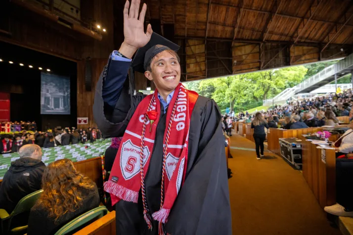 Student waves at crowd during graduation