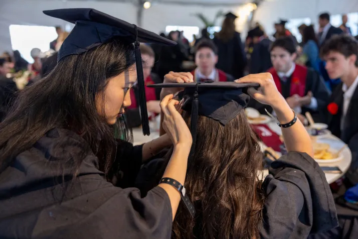 Student helps friend with graduation cap