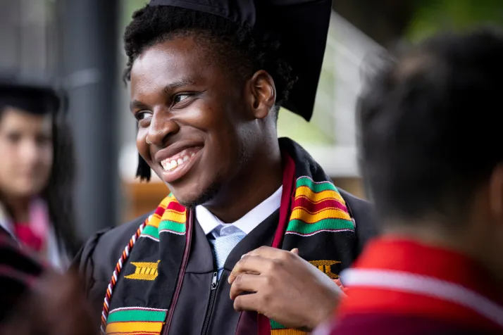 Student smiles while wearing commencement regalia