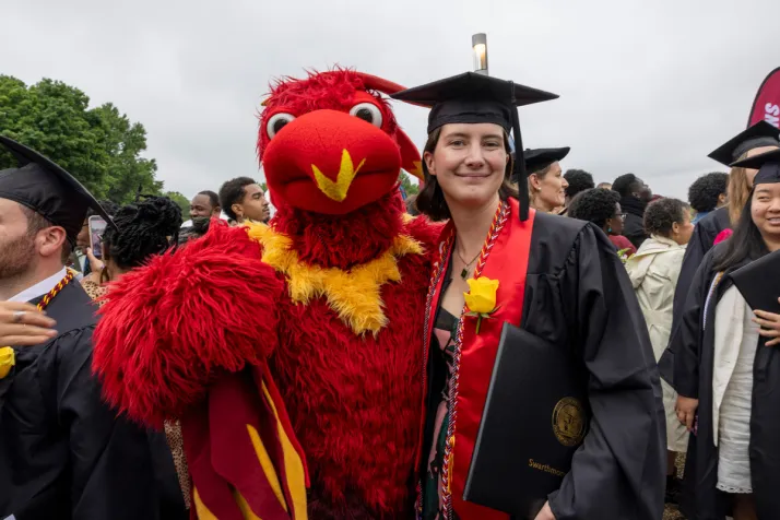 Student poses with Phineas the Phoenix after graduation