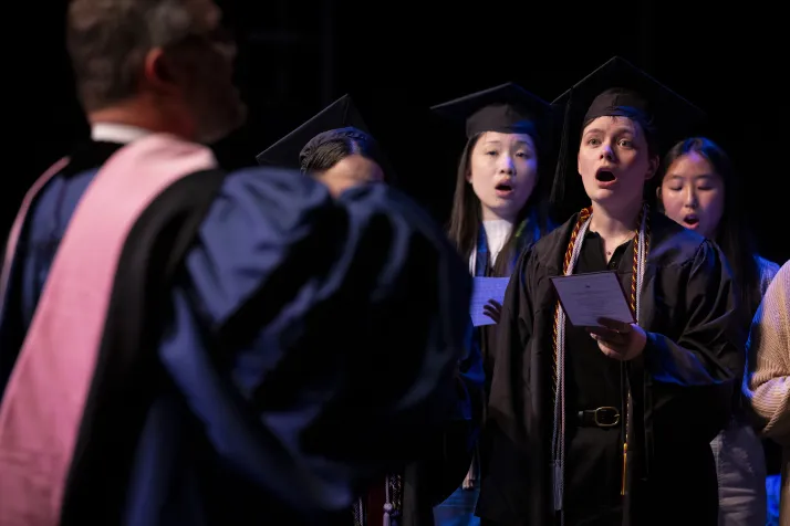 Choir performs while wearing commencement robes