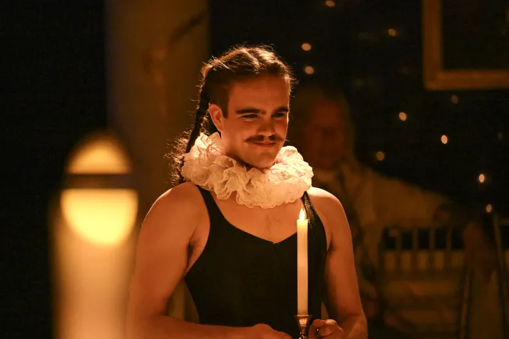Griffin Moore is holding a candle. His hair is in two french braids