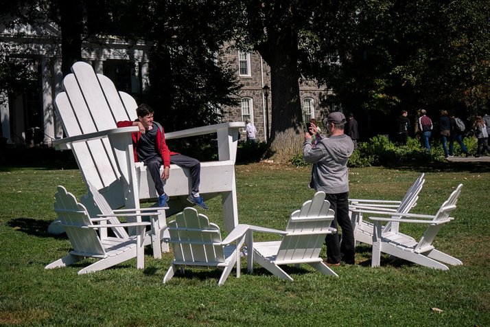 Student takes photo on Adirondack chairs