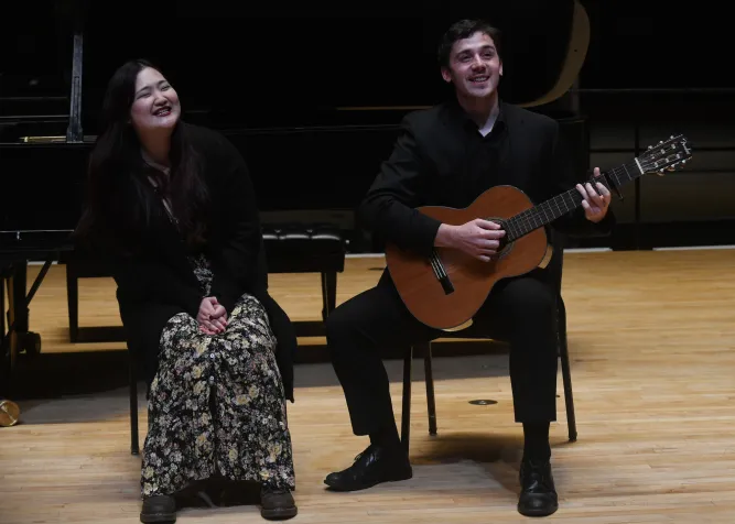 Person sings with another person sitting and playing guitar