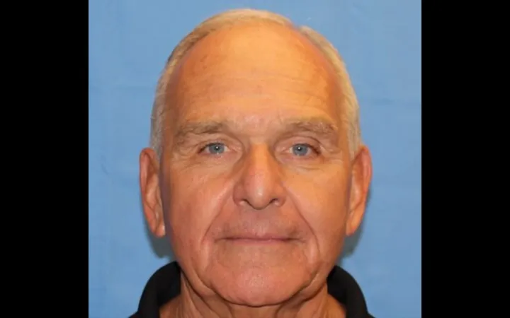 Close shot of a man with close cropped white hair, subtly smiling at the camera.