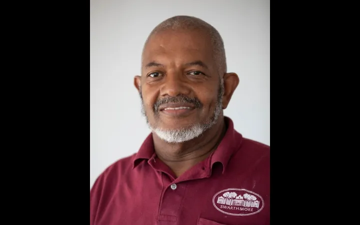 Headshot of an older bald man with a white beard wearing a garnet Swarthmore polo shirt.