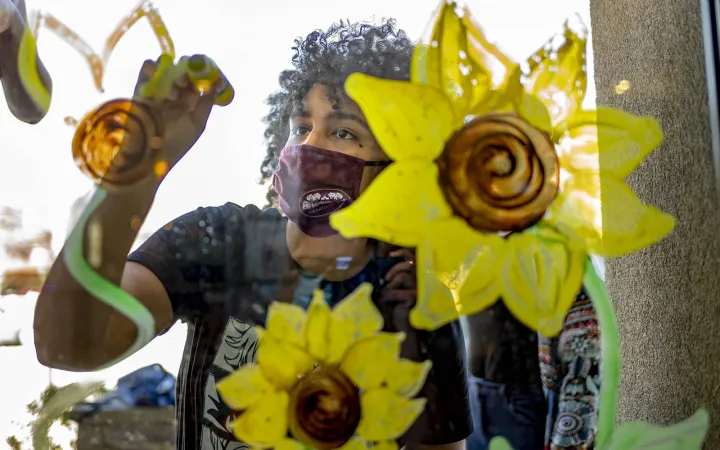 artist painting flowers on glass pane