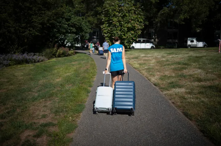 Student drags two suitcases toward dorm on move-in day