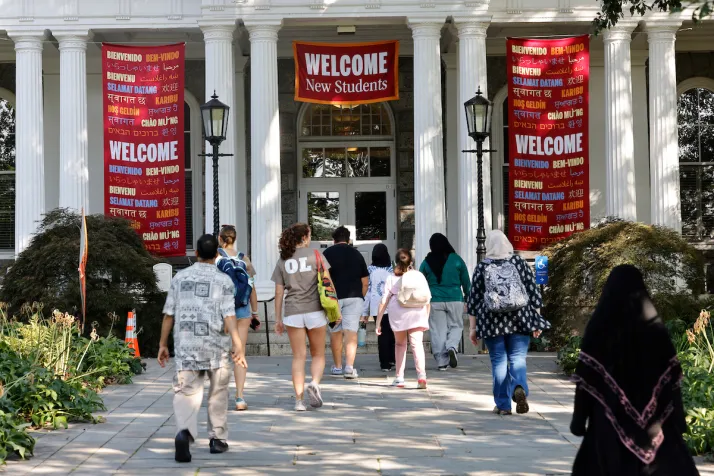 Students walk toward Parrish Hall adorned with banners that say "Welcome New Students"