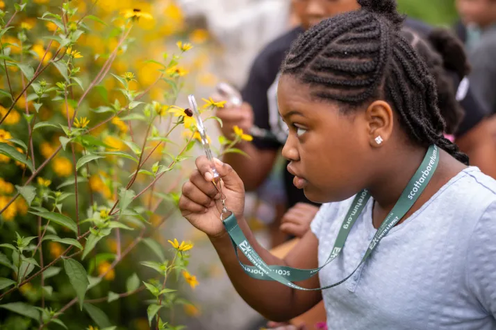 CCC student looks at flower through magnifying glass