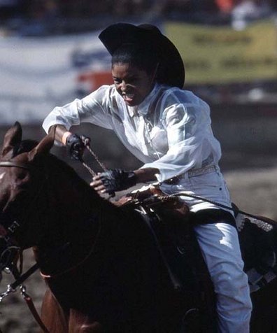 A female participates in a barrel racing event in a California rodeo.