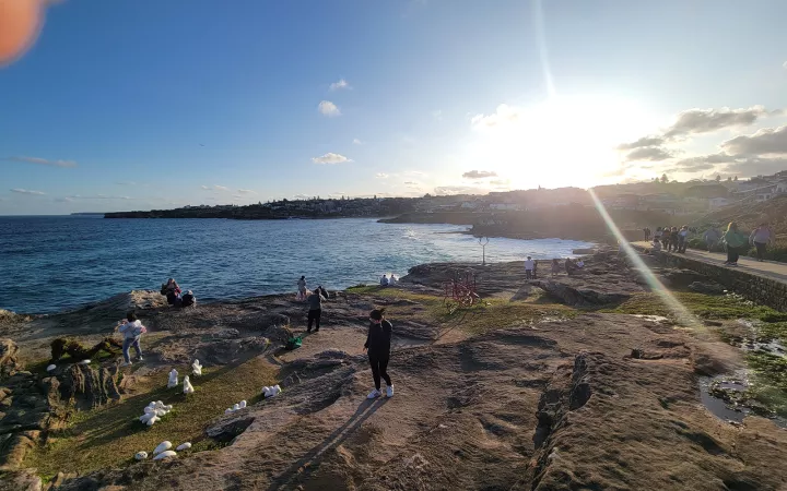 People wandering around rocks on beach (viewed from higher vantage point)