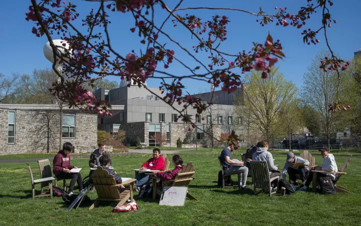 two groups of students sitting outside in chairs 