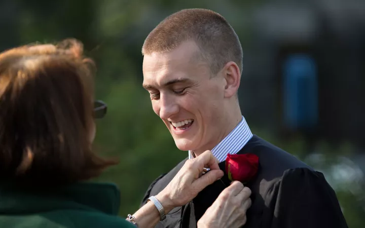 student getting rose attached to gown