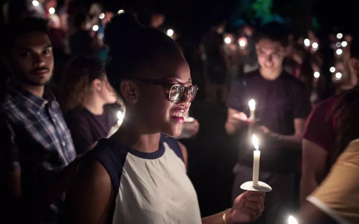 Student holding candle and smiling
