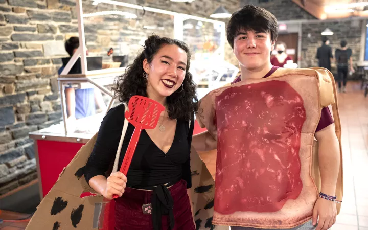 Two students posing in dining hall, one dressed as a sandwich